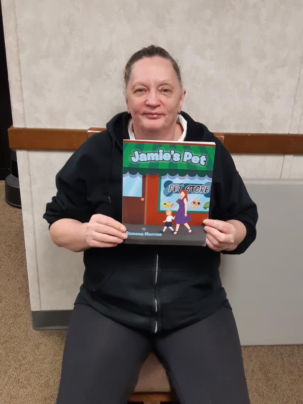 Susan Stone Sitting With A Copy Of Jamie's Pet Children's Book